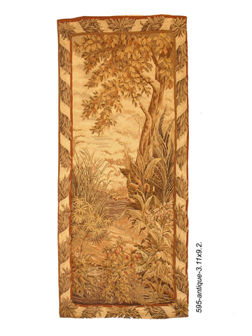 19th century French Verdure tapestry: A wool and silk tapestry depicting a tree in a verdure wooded scene with a wide floral border. 